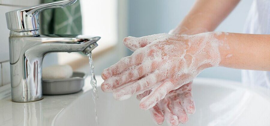 Impregnaty do drewna zawierają oleje, żywice, rozpuszczalniki oraz dodatki biobójcze. Ich zadaniem jest wnikanie w strukturę materiału i zabezpieczanie go przed wilgocią, grzybami oraz promieniowaniem UV. Niestety te same właściwości sprawiają, że preparat łatwo przywiera do skóry i trudno go usunąć zwykłą wodą z mydłem. Kluczowe znaczenie ma szybka reakcja. Świeży impregnat usuwa się znacznie łatwiej niż zaschnięty. Zasady bezpieczeństwa podczas usuwania impregnatu ze skóry Skóra dłoni jest szczególnie narażona na podrażnienia. Impregnaty rozpuszczalnikowe mogą powodować przesuszenie, a w niektórych przypadkach reakcje alergiczne. Nie należy stosować benzyny ekstrakcyjnej, rozpuszczalników nitro ani silnych odtłuszczaczy przemysłowych. Substancje te skutecznie rozpuszczają impregnat, ale jednocześnie uszkadzają naturalną barierę lipidową skóry. Czyszczenie najlepiej przeprowadzać w dobrze wentylowanym pomieszczeniu. Po zakończeniu zawsze należy zastosować preparat nawilżający lub regenerujący. Usuwanie impregnatu metodą tłuszczową - olej, oliwa, masło Większość impregnatów ma charakter olejowy. Oznacza to, że rozpuszczają się w tłuszczach. Zasada „tłuszcz rozpuszcza tłuszcz” sprawdza się w praktyce bardzo dobrze. Olej roślinny, oliwa z oliwek lub nawet masło należy nanieść obficie na zabrudzone miejsca i wmasowywać przez kilka minut. Preparat zacznie się rozpuszczać i oddzielać od skóry. Następnie dłonie wyciera się ręcznikiem papierowym i myje ciepłą wodą z dodatkiem mydła. W przypadku mocnych zabrudzeń czynność można powtórzyć. Płyn do mycia naczyń z dodatkiem substancji ściernej Jeżeli impregnat częściowo zaschnął, pomocna może być metoda łącząca działanie odtłuszczające i mechaniczne. Do płynu do mycia naczyń dodaje się cukier lub drobną sól. Powstaje pasta o właściwościach peelingujących. Wcieranie jej w skórę pomaga rozbić warstwę impregnatu i jednocześnie rozpuścić jego składniki tłuszczowe. Po kilku minutach dłonie należy dokładnie spłukać i osuszyć. Specjalistyczne pasty BHP do usuwania trudnych zabrudzeń Pasty do mycia rąk stosowane w warsztatach samochodowych są przystosowane do usuwania smarów, olejów i farb. W wielu przypadkach skutecznie radzą sobie także z impregnatem do drewna. Zaletą takich produktów jest połączenie składników rozpuszczających z drobnym ścierniwem. Jednocześnie są one łagodniejsze dla skóry niż przemysłowe rozpuszczalniki. Produkt należy wmasować w suche dłonie, a następnie spłukać wodą. Alkohol izopropylowy - rozwiązanie pomocnicze Alkohol izopropylowy może rozpuścić niektóre składniki impregnatu, szczególnie jeśli preparat był na bazie rozpuszczalników. Należy jednak stosować go ostrożnie i w niewielkich ilościach. Środek nakłada się na wacik i delikatnie przemywa zabrudzoną skórę. Po użyciu konieczne jest dokładne umycie dłoni i zastosowanie kremu regenerującego, ponieważ alkohol silnie odtłuszcza i wysusza naskórek. Metoda ta nie powinna być stosowana często. Czego nie stosować do czyszczenia skóry Nie zaleca się używania: benzyny ekstrakcyjnej, rozpuszczalników nitro, acetonu technicznego, silnych środków do czyszczenia pędzli. Substancje te mogą wywołać podrażnienia, mikrouszkodzenia skóry oraz reakcje alergiczne. Krótkotrwała skuteczność nie rekompensuje ryzyka uszkodzenia naskórka. Pielęgnacja skóry po usunięciu impregnatu Po dokładnym oczyszczeniu dłoni należy przywrócić im odpowiedni poziom nawilżenia. Wskazane jest zastosowanie kremu regenerującego z gliceryną, alantoiną lub pantenolem. Jeżeli skóra stała się zaczerwieniona lub podrażniona, warto przez kilka godzin unikać kontaktu z detergentami i ekspozycji na słońce. W przypadku silnego pieczenia lub reakcji alergicznej konieczna jest konsultacja z lekarzem. Zapobieganie zabrudzeniom podczas pracy z impregnatem Najskuteczniejszą metodą jest profilaktyka. Podczas impregnacji drewna należy stosować rękawice ochronne odporne na działanie substancji chemicznych. Najlepiej sprawdzają się rękawice nitrylowe. Warto również mieć pod ręką papierowe ręczniki i środek czyszczący, aby usuwać zabrudzenia natychmiast po ich powstaniu. Im krótszy kontakt impregnatu ze skórą, tym łatwiejsze późniejsze czyszczenie. Odpowiednia ochrona dłoni znacząco zwiększa komfort pracy i ogranicza ryzyko podrażnień.